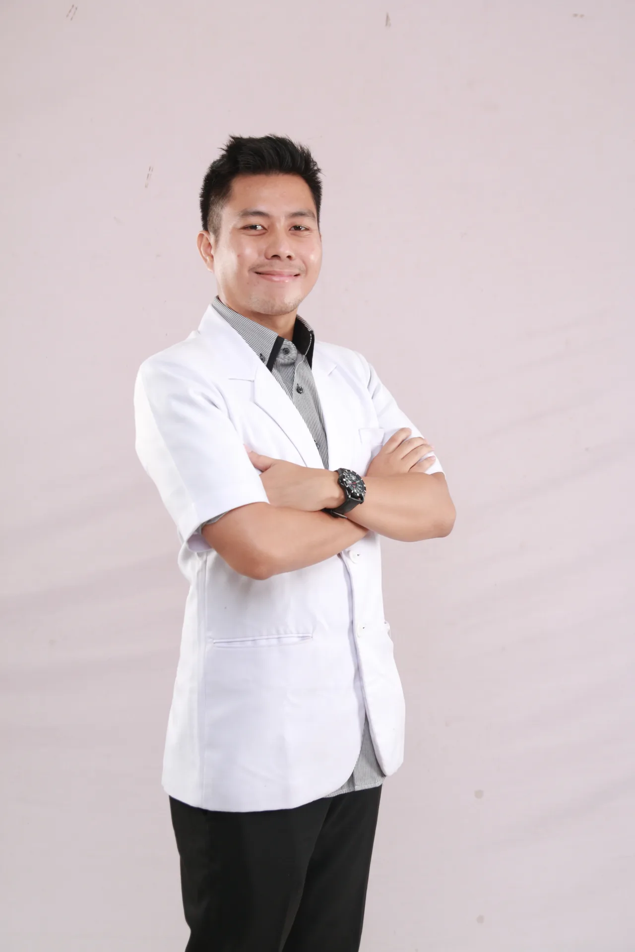 A healthcare professional in a white coat standing with arms crossed